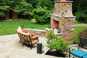 picture of an outdoor fire bit in the corner of a backyard patio with hardscaping, patio furniture, and great outdoor living space - DeMichele Inc Media, PA